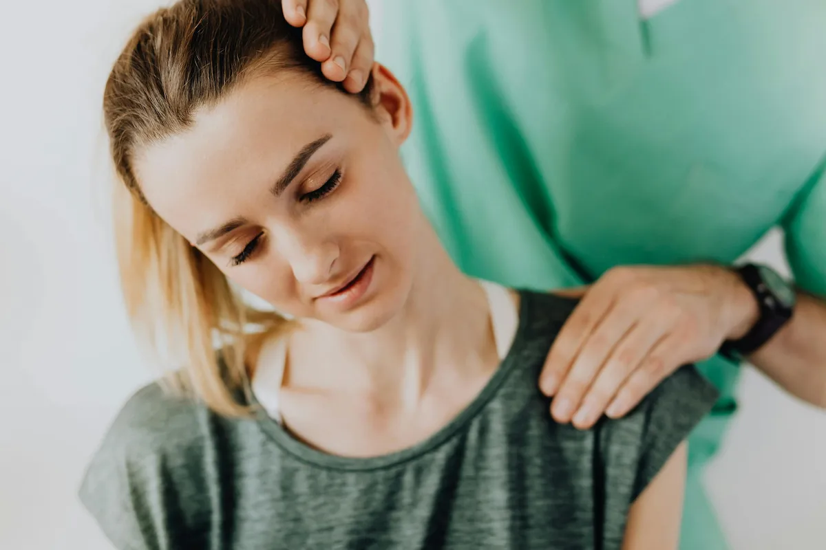 Woman receiving a chiropractic neck adjustment from a practitioner, showing relief and relaxation