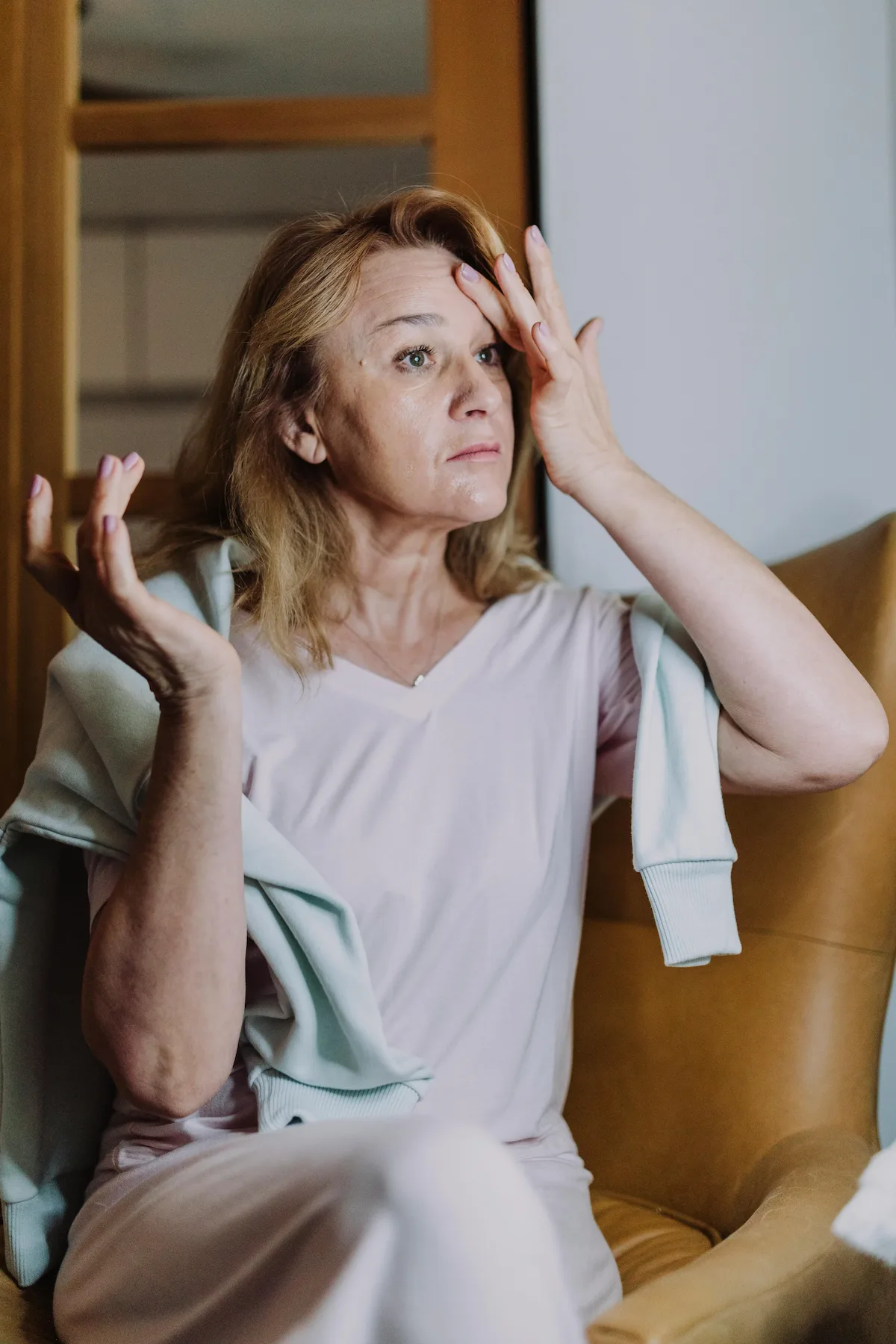 Woman holding her forehead in pain, indicating a headache or migraine