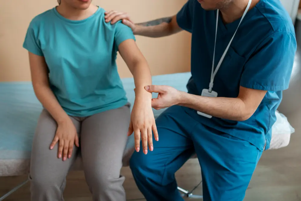 A medical professional in blue scrubs gently examines a patient’s forearm and wrist, with one hand on the patient’s shoulder, assessing for a possible pinched nerve.