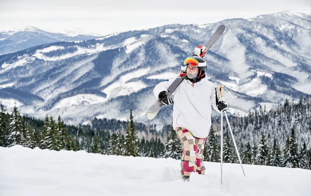 Skier standing on snowy mountain with ski gear