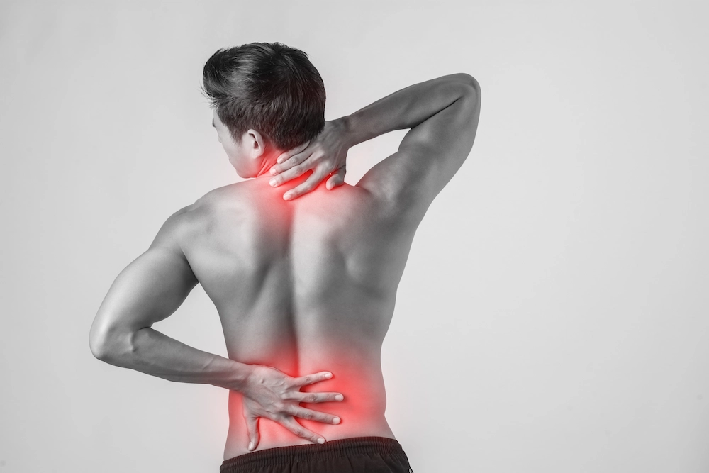 Person holding back in pain while identifying source of muscle or spinal discomfort