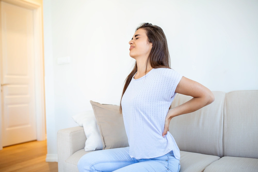 Person holding their lower back and hip due to SI joint pain