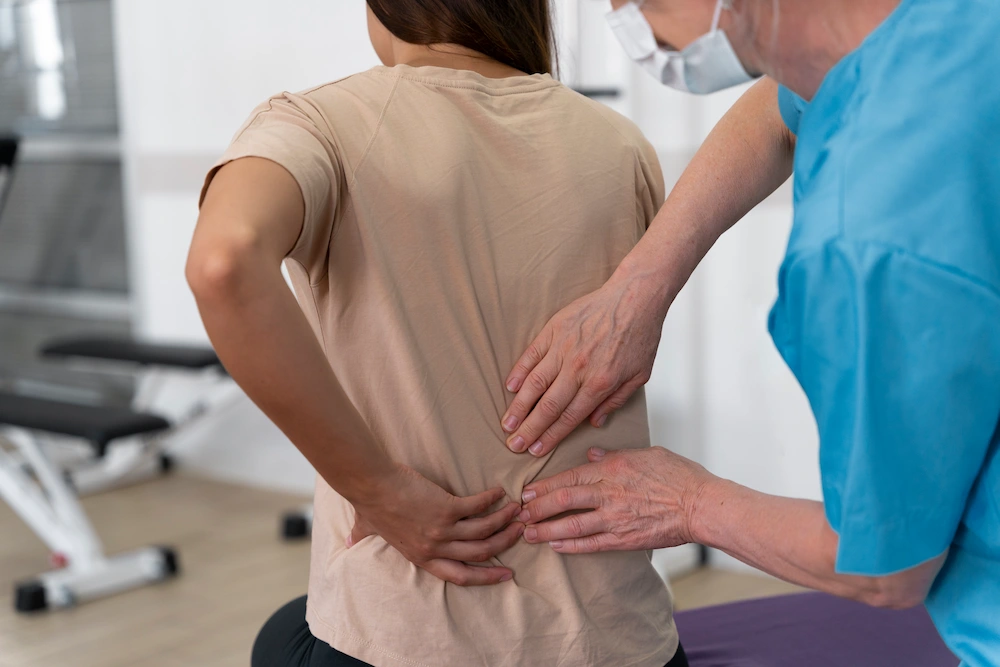 Healthcare professional explaining spinal stenosis using a spine model